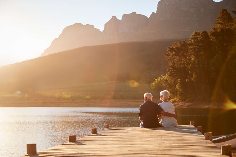 Romantic senior couple sitting on a wooden jetty by a lake