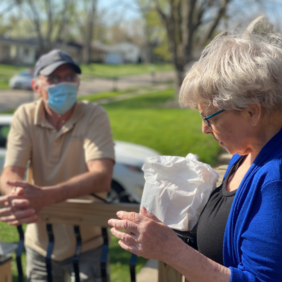 Person holding a lunch bag while talking to a friend