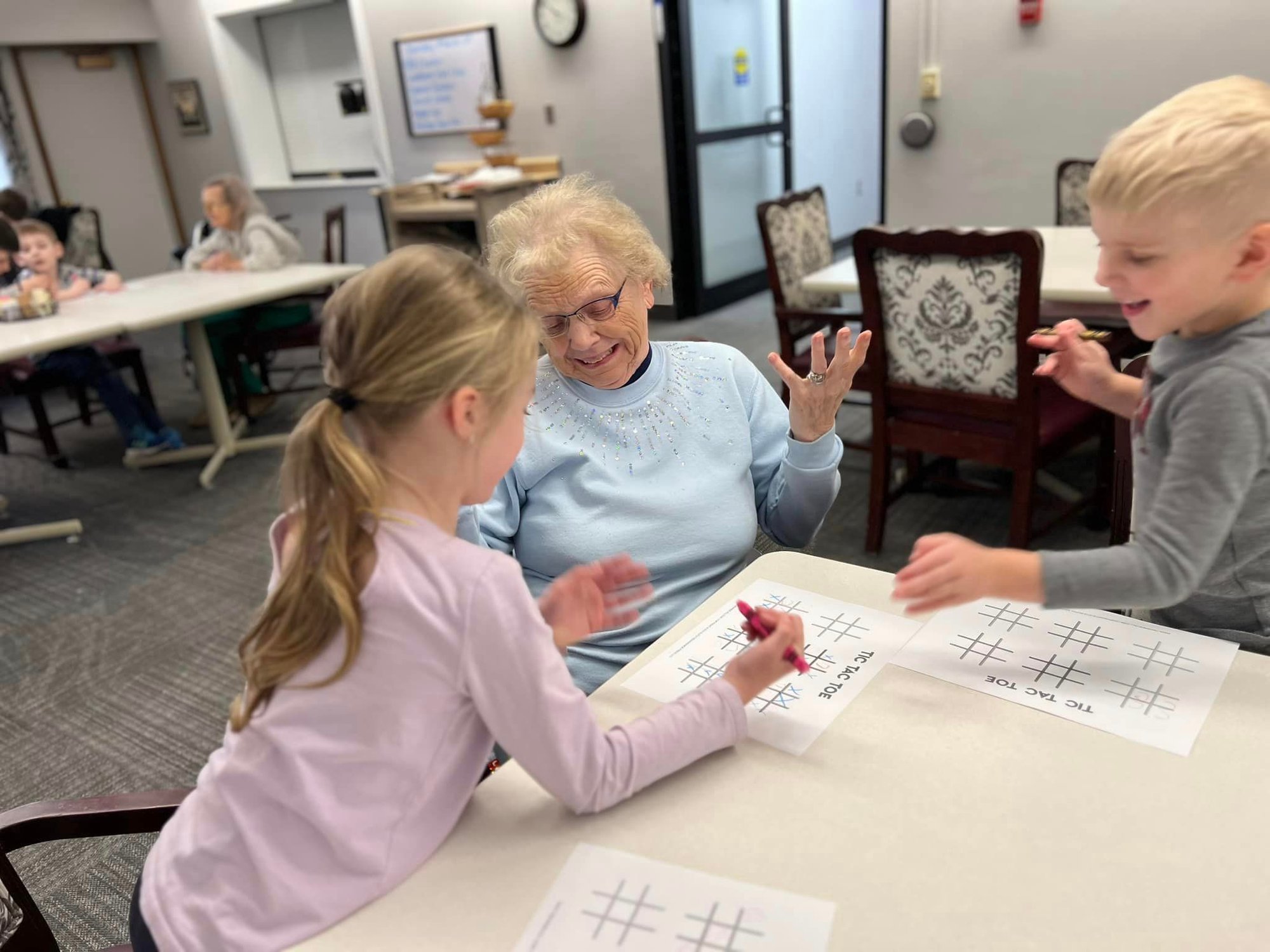 Grandmother playing tic-tac-toe with two of her young grand children