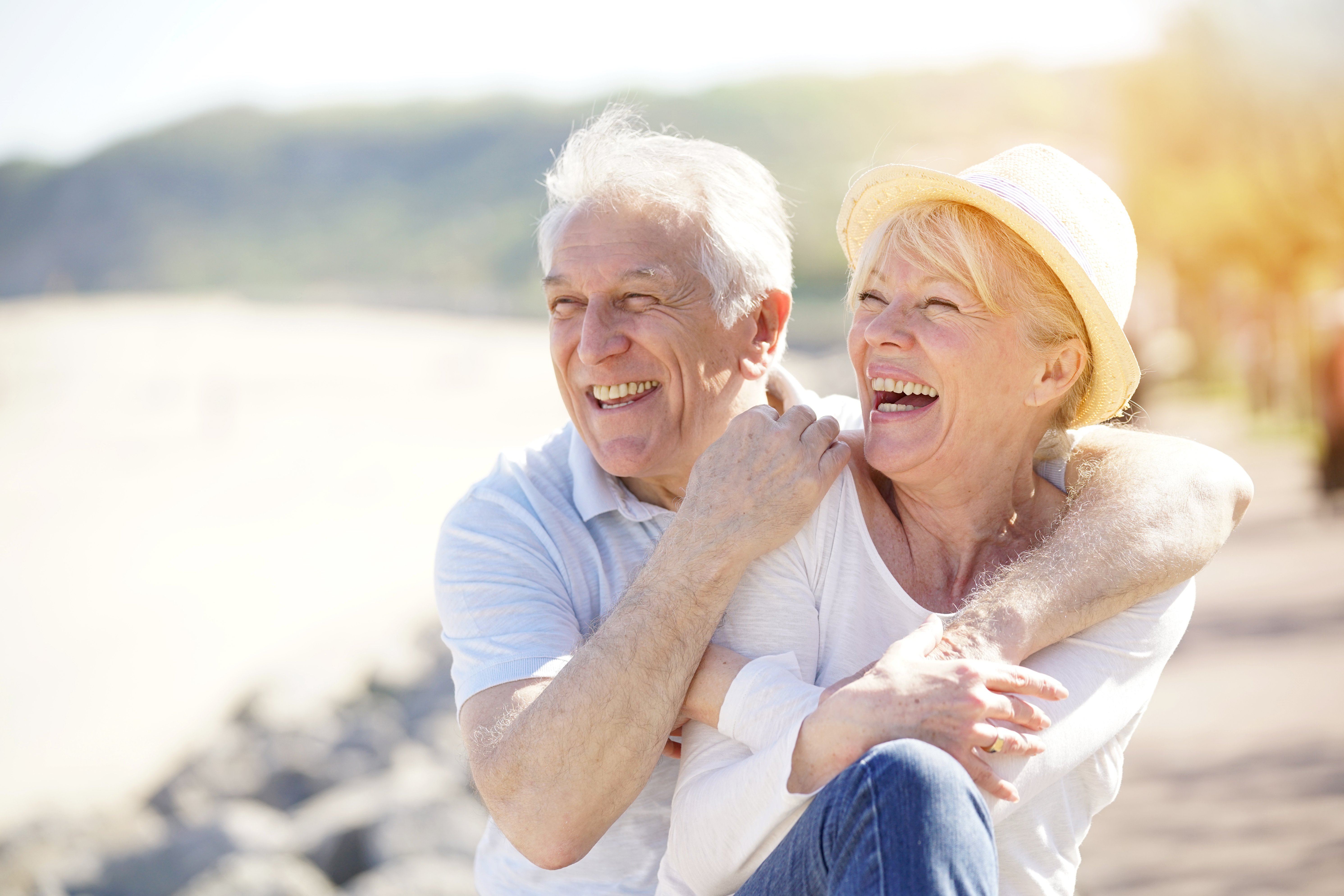 Two older adults laughing on a beach together