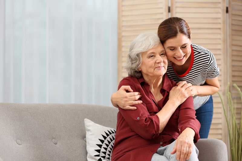 Women smiling and embracing senior grandmother