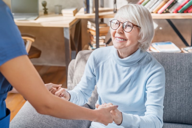 An at-home senior care nurse holding an older woman’s hands.