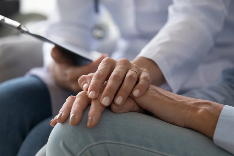 A young doctor holding a senior patient’s hand. 