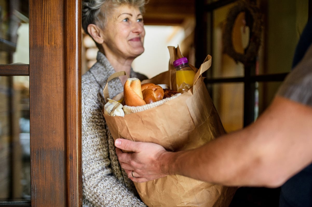 A senior woman receiving a bag of groceries.