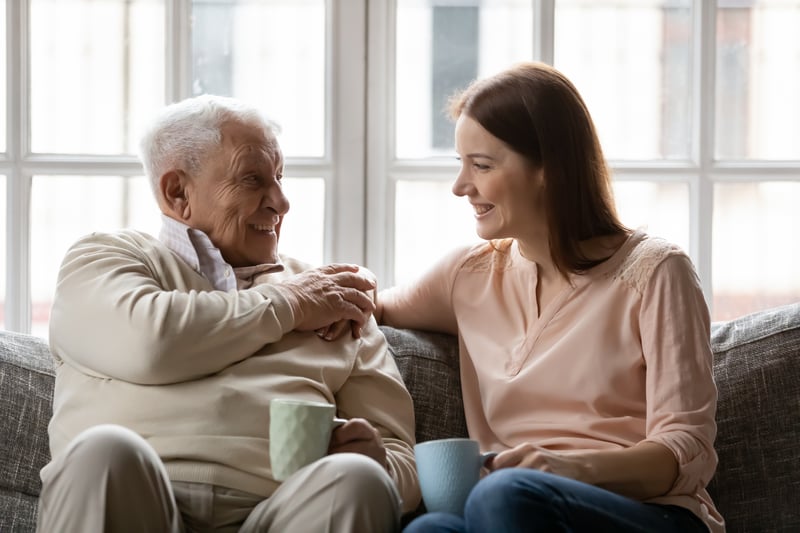 Happy smiling elderly father enjoy conversation with beloved grown daughter discuss news for cup of tea