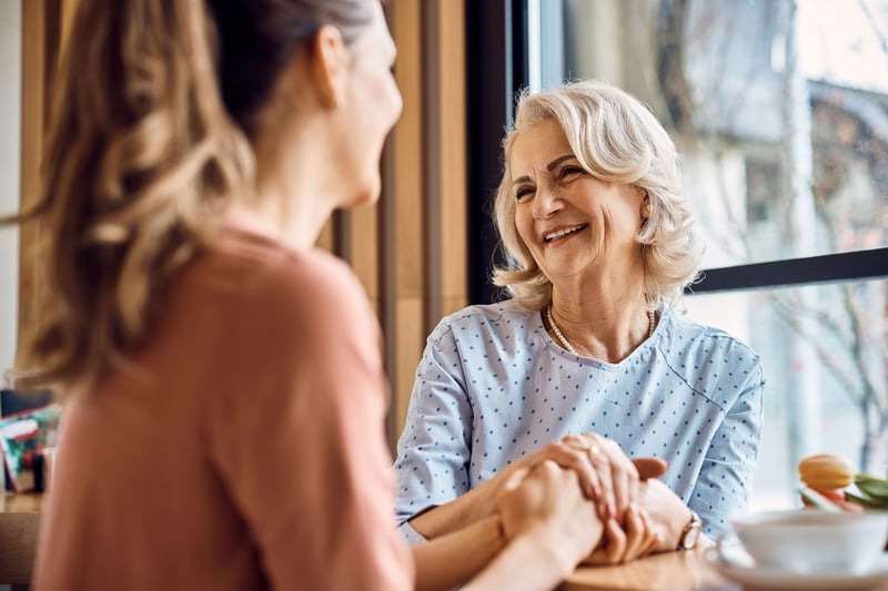 A happy older woman enjoys a conversation with her adult daughter.