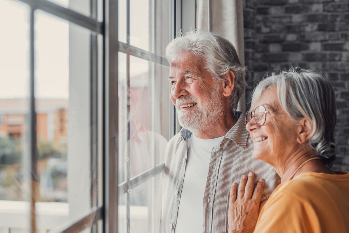 A senior couple looking out the window.