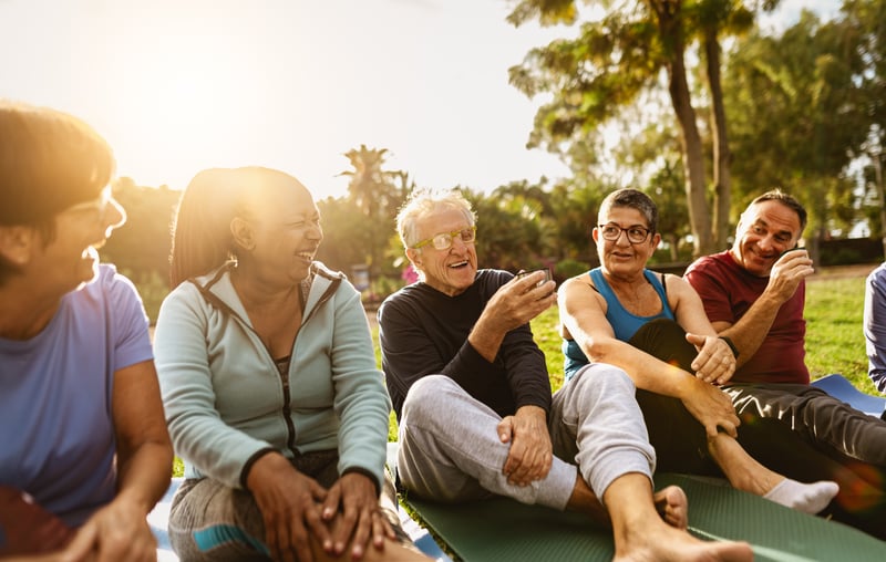 A group of seniors laughing together at a public park.