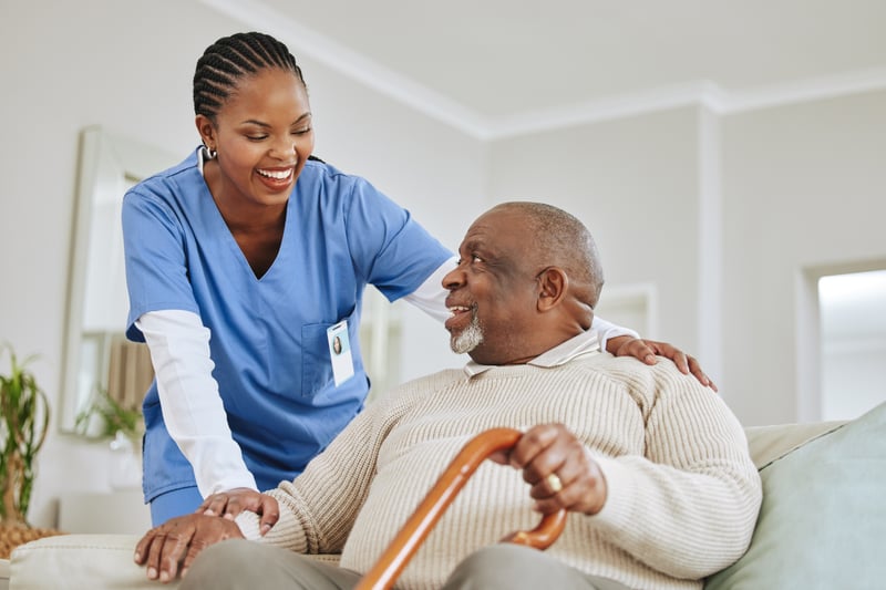 A healthcare worker smiling and providing a helping hand to a senior man.