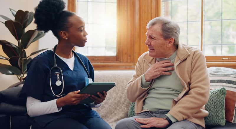 Technology, medicine and appointment with a nurse talking to an elderly patient on the sofa.