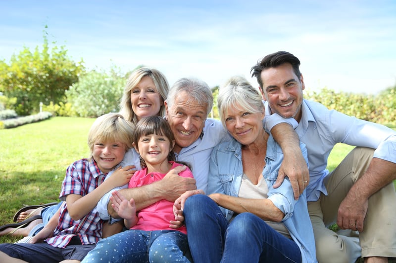 Multiple generations of one family sitting together and smiling for a photo.