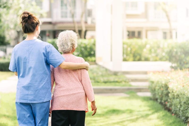 Senior and caretaker standing outside