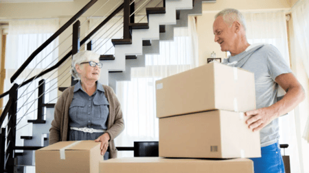 A senior couple packing cardboard boxes in preparation for downsizing their home.