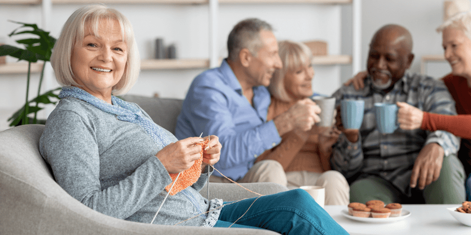 A woman knitting with friends in a senior living community