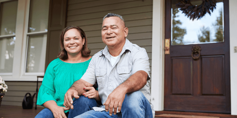 senior couple sitting on the front steps of a house