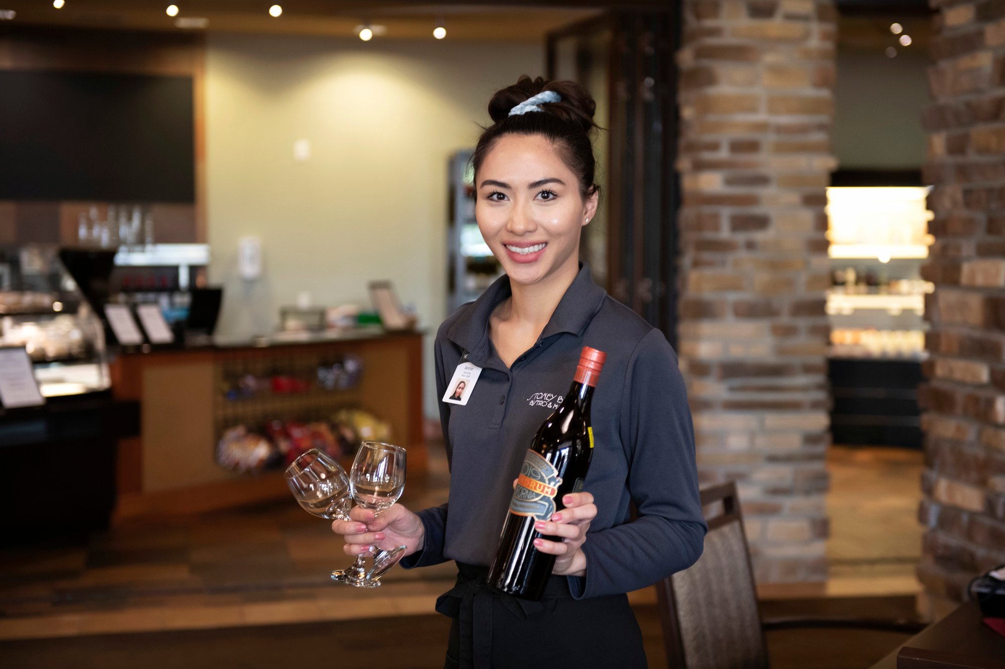 Waitress holding a bottle of wine and glasses