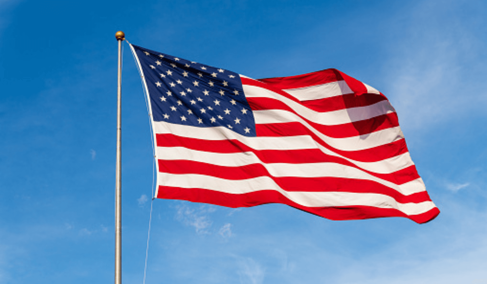 The United States flag waving against a clear blue sky.