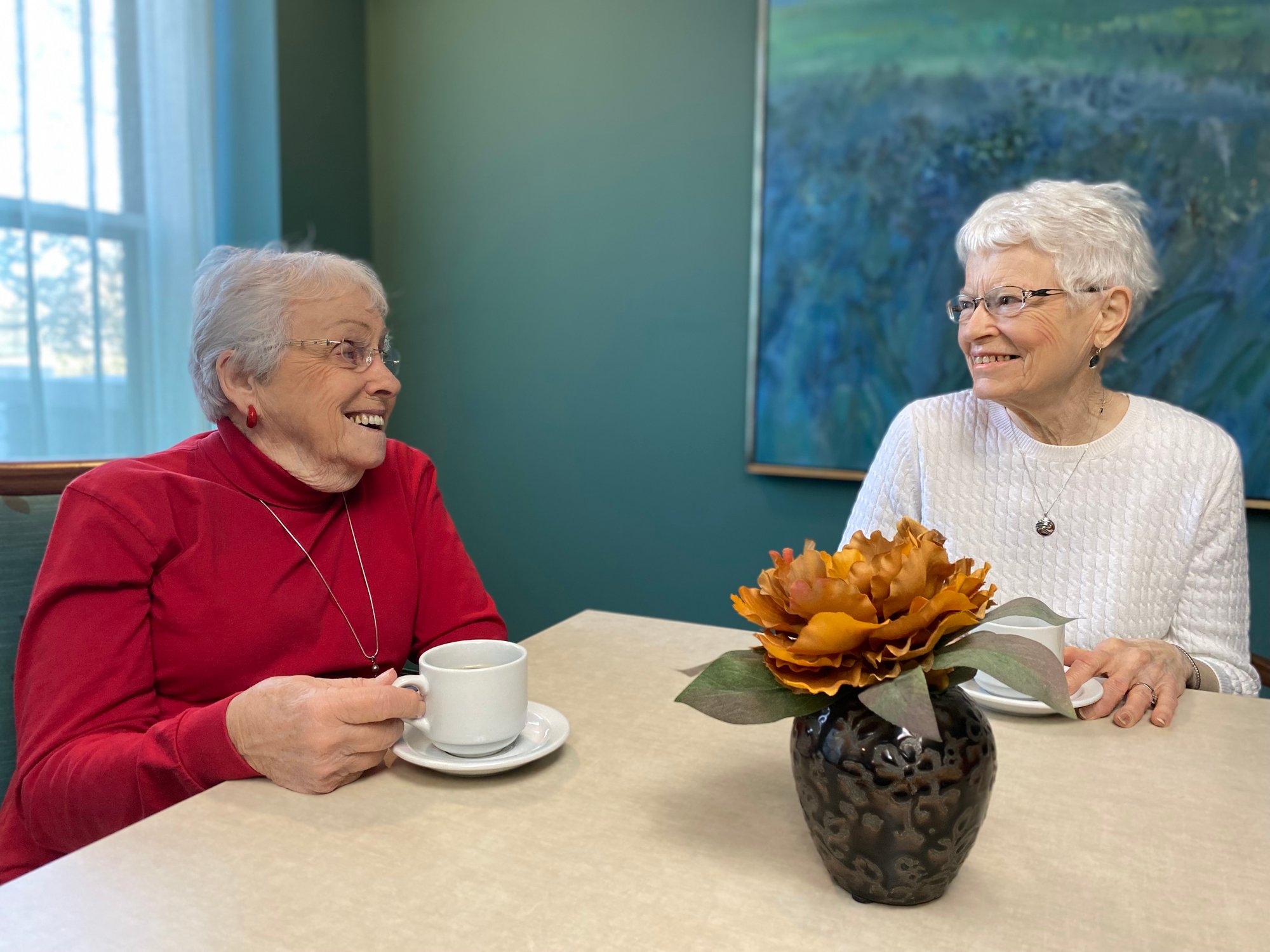 Two senior women drinking coffee at a table