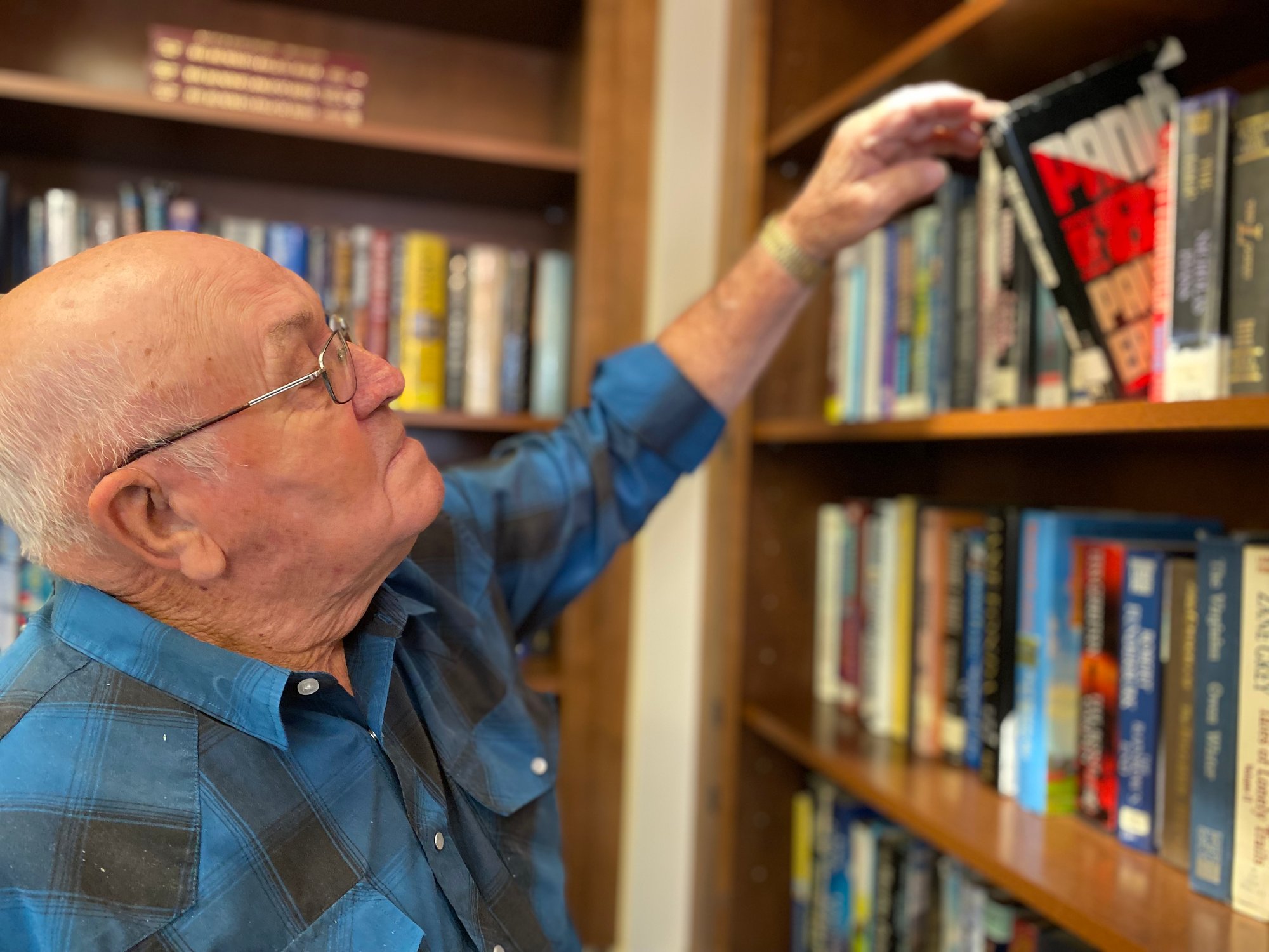 senior man picking book out of library