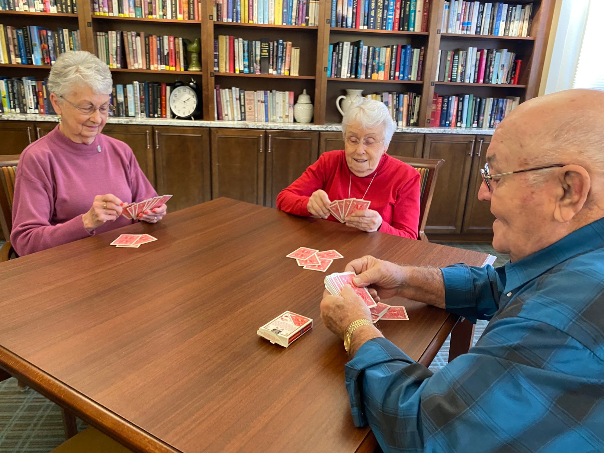 Friends playing cards at a table in the library 