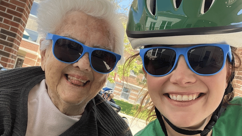 Two people wearing sunglasses and bike hats and grinning at the camera