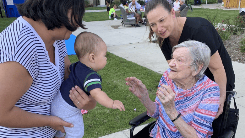 A woman in a wheelchair greeting an infant