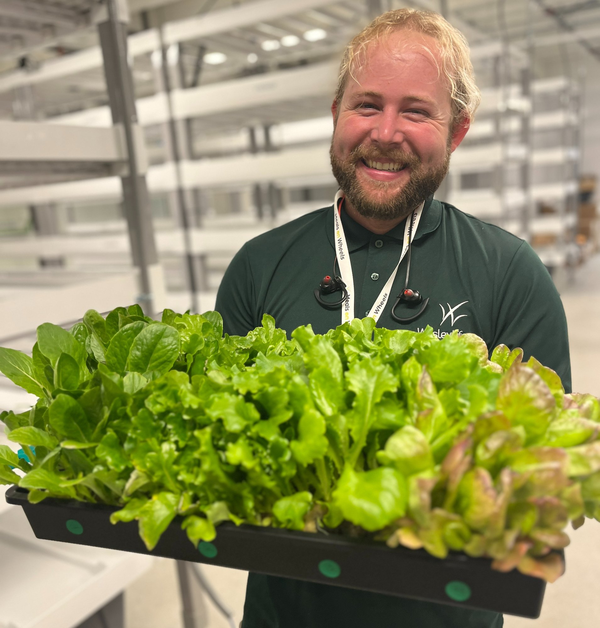 A farmer smiling and holding a tray of hydroponic greens