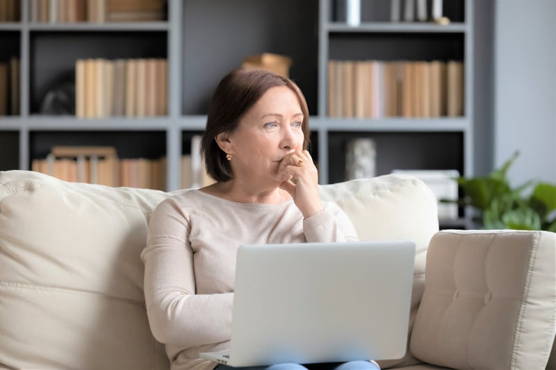 Woman thinking while searching for options on her computer