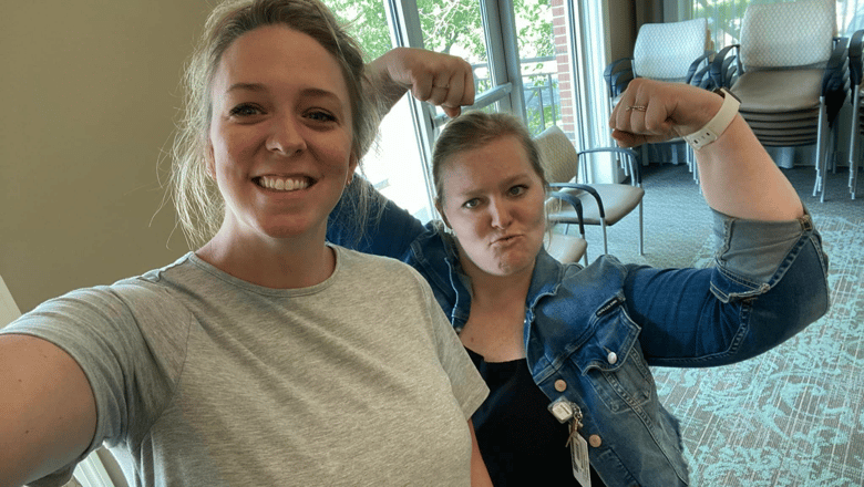 One team member taking a selfie while another curls her biceps in the background