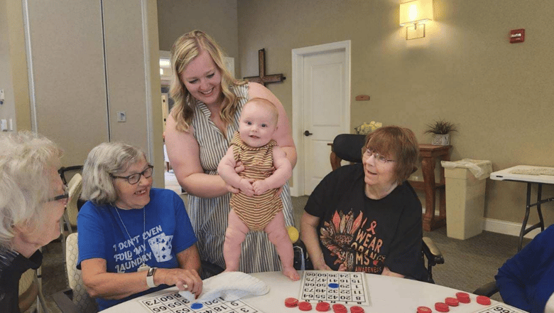 A team member showing a baby to a group of senior residents
