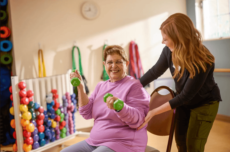 Happy older woman working out with weights with a wellness coach