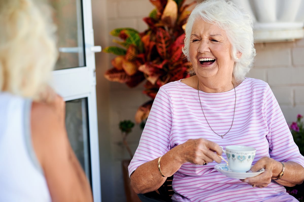 resident laughing with friend while drinking coffee