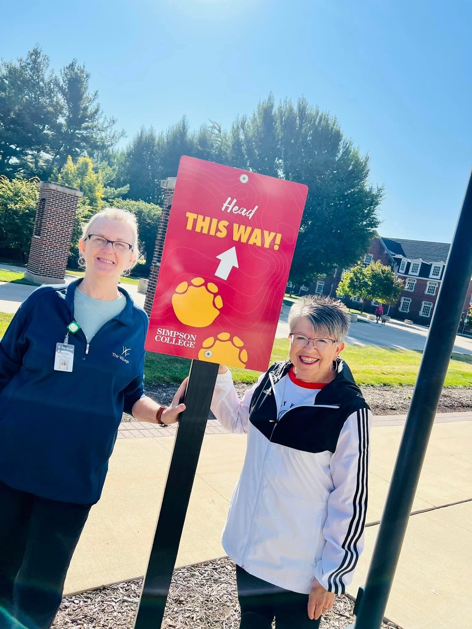 resident and employee smiling with a sign for Simpson College