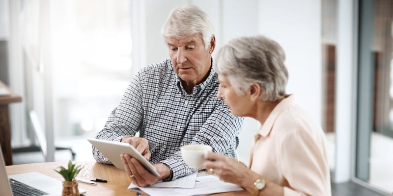 Senior couple looking at a tablet discussing finances