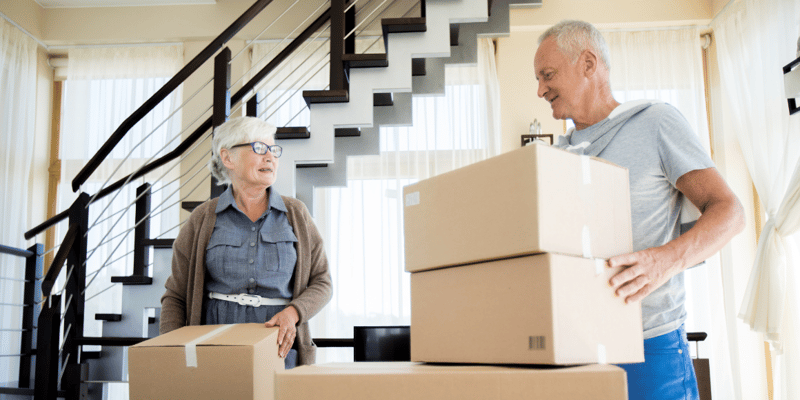 A senior couple packing cardboard boxes in preparation for downsizing their home.