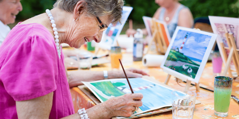 A senior woman watercolor painting with her friends.