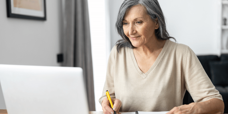 An older woman researching senior living costs on her computer.