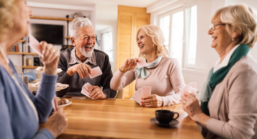 A group of senior friends having fun while playing cards around a table