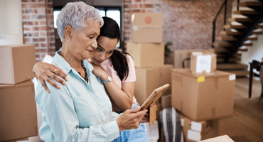 Mother and daughter looking at picture while packing boxes to move to assisted living.