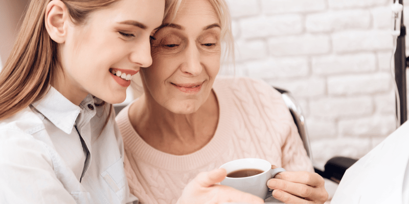 A smiling senior and younger woman looking at photo album together.