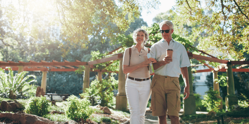 A happy, older couple walking though a park during springtime.