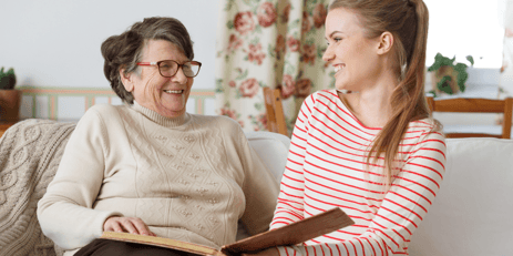 mother and daughter sitting on couch while reading a book