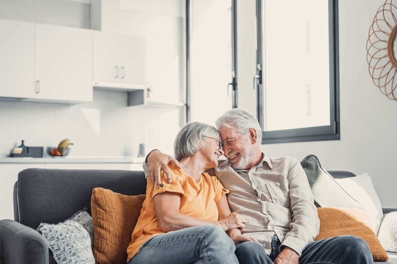 A happy senior couple embracing on their couch.