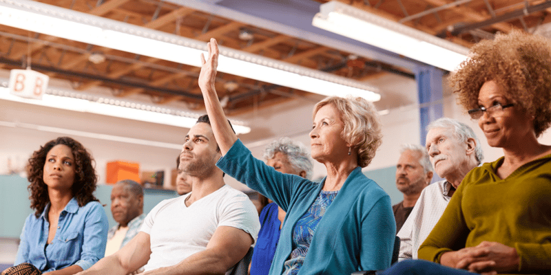 Senior Woman raising her hand in a crowd