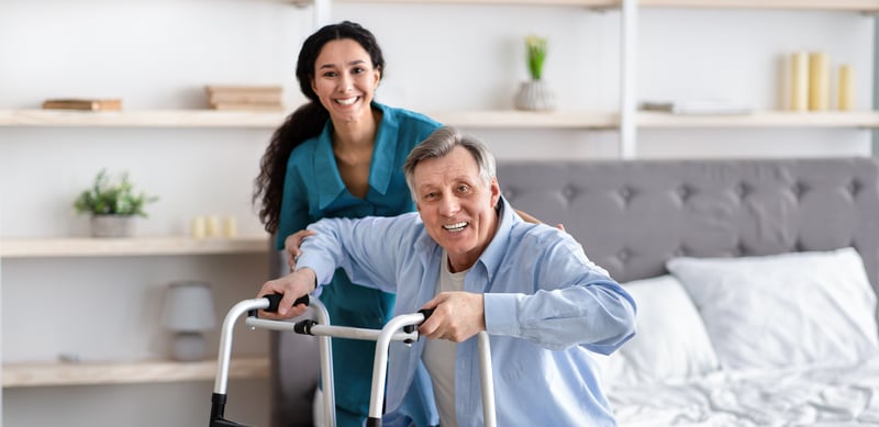 caretaker helping senior man with a walker