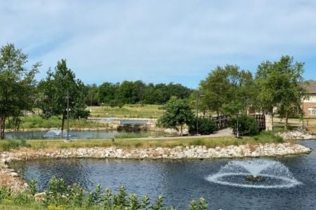 a walking trail around pond with a fountain