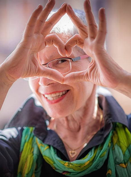 Cute senior old woman making a heart shape with her hands and fingers