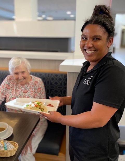 Elderly woman at the table and a waitress smiling