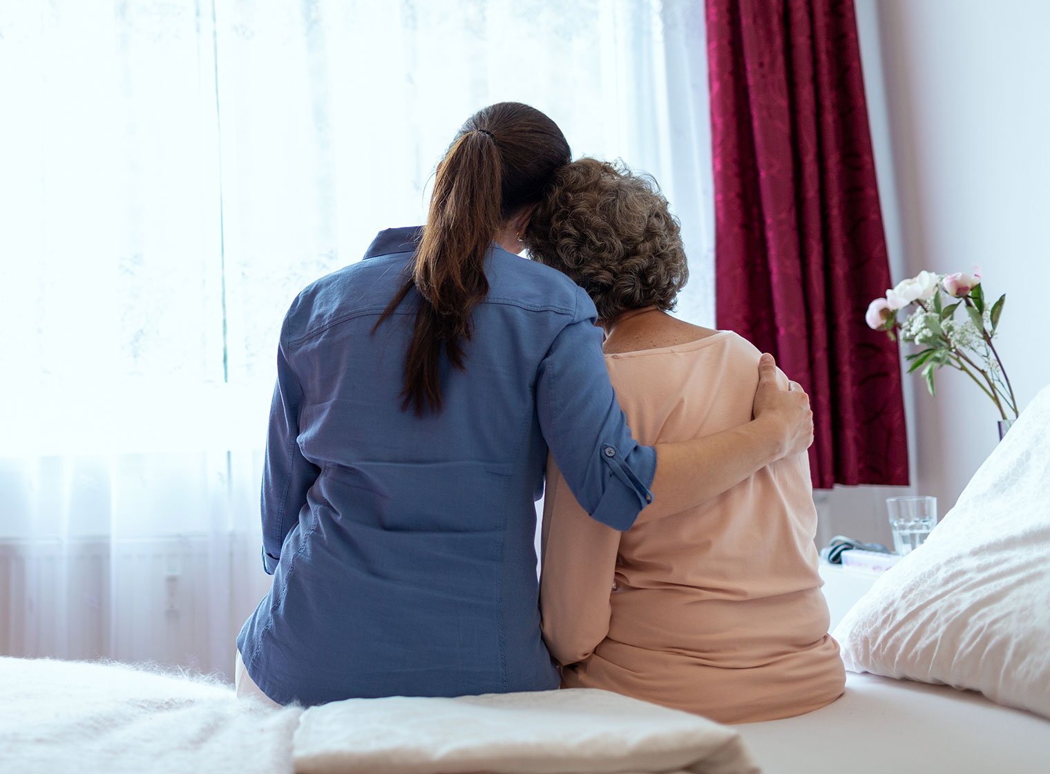 Female Home Nurse Hugging Elderly Woman on Bed