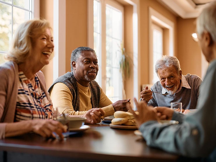 Group of cheerful senior people enjoy in conversation during lunch at nursing home